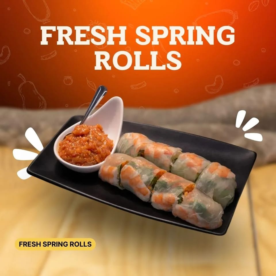 Fresh spring rolls with shrimp and vegetables on a black plate with a side of red dipping sauce.