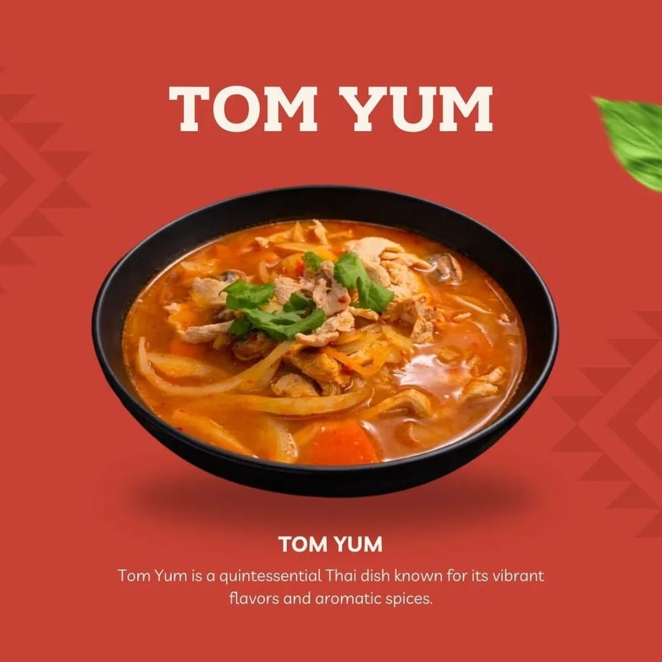 Vibrant orange-red Tom Yum soup in a black bowl, garnished with meat and fresh cilantro.