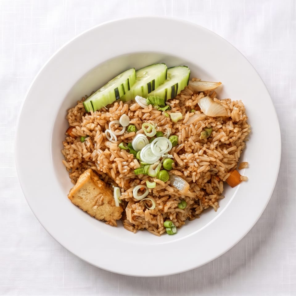 Fried rice with tofu, peas, onions, and green onions, garnished with cucumber slices.
